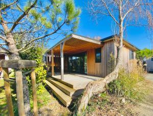 a home with a wooden porch and a tree at Camping Paradis 4 étoiles A La Corniche La Rochelle Angoulins in Angoulins-sur-Mer
