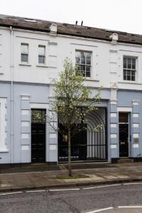 a white building with black doors on a street at Queens Park by Viridian Apartments in London