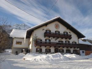 ein großes Gebäude im Schnee mit einem Hund davor in der Unterkunft Kastnerhof 