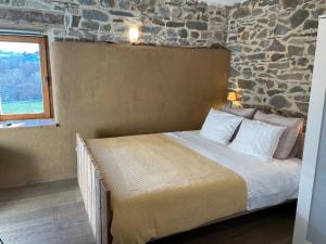 een bed in een kamer met een stenen muur bij La Bushaye in Aubel