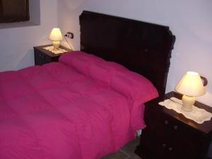 una camera con letto rosa e 2 comodini di Cuevas Rio Baza a Baza