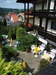 un patio con sillas y mesas blancas y sombrillas amarillas en Hotel Schloessmann Garni, en Bad König
