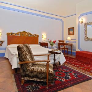 a bedroom with a bed and a chair and a table at Il Rondò Boutique Hotel in Montepulciano