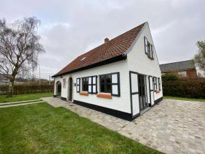 uma casa branca com janelas pretas e um quintal em Vakantiehuis Cas.tard em Zillebeke