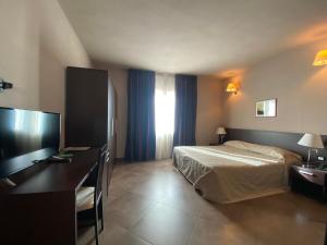 a bedroom with a bed and a desk and a television at Hotel Le Badie in Val di Perga