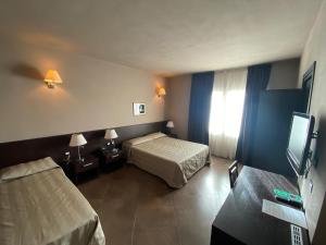 a hotel room with two beds and a flat screen tv at Hotel Le Badie in Val di Perga