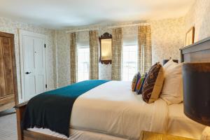 a bedroom with a large white bed and windows at Shelter Harbor Inn in Westerly