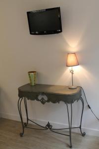 a table with a lamp and a tv on a wall at Hôtel Restaurant Aux Genêts d'Or in Mandailles
