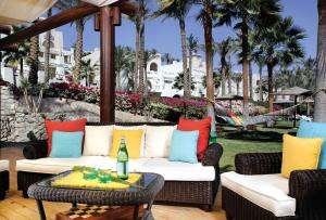 eine Terrasse mit einem Sofa, Stühlen und Palmen in der Unterkunft Grand Rotana Resort & Spa in Sharm El Sheikh