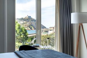 
a person laying on a bed in front of a window at Lasala Plaza Hotel in San Sebastián

