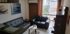 ein Wohnzimmer mit einem Ledersofa und einem Stuhl in der Unterkunft Departamento Equipetrol Empresarial Familiar in Santa Cruz de la Sierra