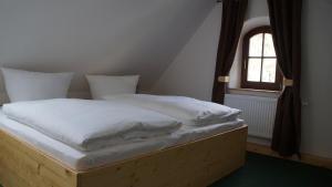 Una cama con sábanas blancas y una ventana en una habitación en Ferienhaus Mutter Anna's Refugium, en Stolpen