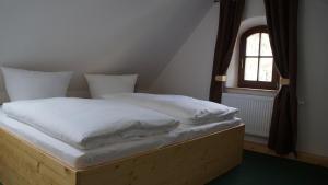 a bed with white sheets and a window in a room at Ferienhaus Mutter Anna's Refugium in Stolpen