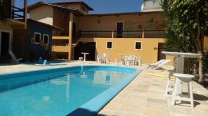 a pool with chairs and a table and a house at Pousada Dos Girassois Prado in Prado