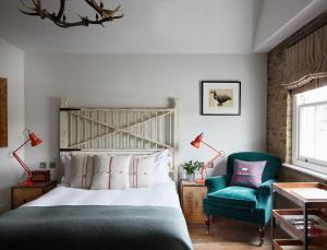 a bedroom with a bed, chair, lamp, and window at Artist Residence London in London