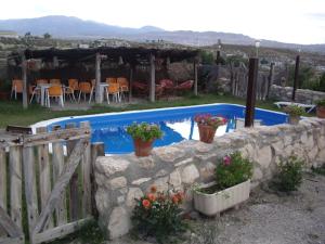 una piscina con un muro in pietra e alcune piante di Cuevas Rio Baza a Baza Altre 20 foto