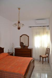 um quarto com uma cama, um espelho e uma cadeira em Su Muscadeddu em Tertenìa