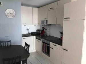 uma cozinha com armários brancos e uma mesa preta em Au Coeur de Colmar em Colmar