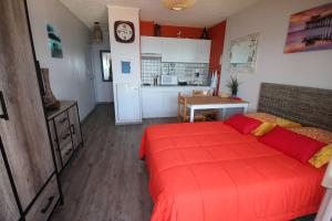 Cet appartement comprend une chambre avec un lit rouge et une cuisine. dans l'établissement Studio climatise 2 couchages, Wifi, VUE MER directement à PORTIRAGNES PLAGE LXBFM10, à Portiragnes