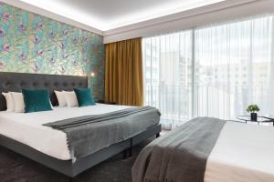 a bedroom with a large bed and a large window at Hôtel Charlemagne by Happyculture in Lyon
