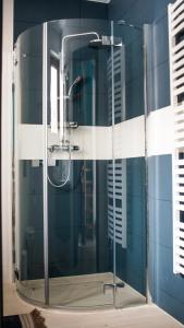 a glass shower in a bathroom with blue tiles at OSADA Rokicie in Kluszkowce