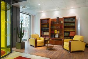 een bibliotheek met twee stoelen, een tafel en boekenplanken bij Hôtel Charlemagne by Happyculture in Lyon