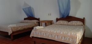 two beds in a room with blue curtains at Centro Ecoturistico Ya´ajche in Lacanjá