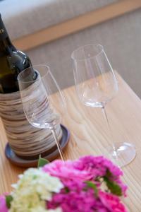 Dois copos de vinho, uma garrafa e flores numa mesa. em Hotel-Restaurant-Café Krainer em Langenwang
