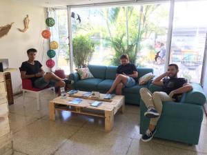 three people sitting on couches in a living room at Lost in San Jose Hostel & Suites in San José