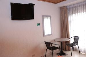 een kamer met een tafel en stoelen en een televisie aan de muur bij Hoteles Bogotá Inn Galerías in Bogota
