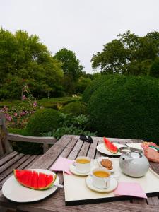 a wooden table with plates of watermelon and cups of coffee at B&B côté jardin in Villers-Outréaux