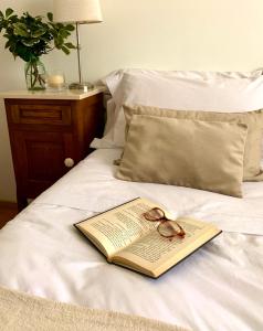 a book and glasses on top of a bed at Hotel Olijnyk in Rosario del Tala