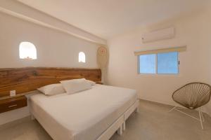 a bedroom with a white bed and a chair at Hotel Caracol Puerto Morelos in Puerto Morelos