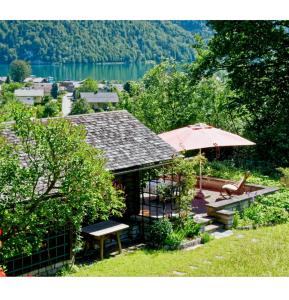 a house with an umbrella and a table and bench at Sonnhof in Sankt Gilgen