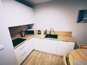 a kitchen with white cabinets and a sink and a table at Apartament w Rezydencji Park in Mielno