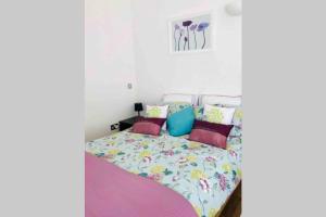 a bedroom with a bed with colorful pillows at Great couples accommodation with beautiful sea view in Lyme Regis