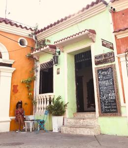 a woman sitting in front of a building at Casa Mamá Waldy Hostel in Cartagena de Indias