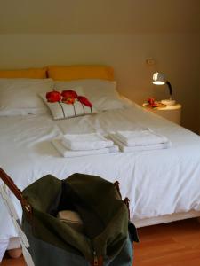 a bed with white sheets and red roses on it at B&B côté jardin in Villers-Outréaux