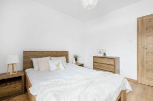 sypialnia z białym łóżkiem z drewnianym zagłówkiem w obiekcie GoldAparts Gdańska w Łodzi