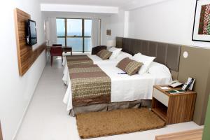 a hotel room with a bed, desk, chair and window at Nobile Suítes Executive in Recife