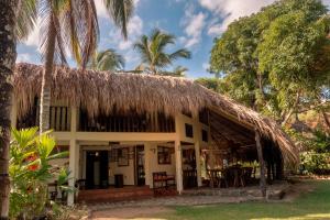 a house with a thatched roof and palm trees at Hotel Casalina in Palomino