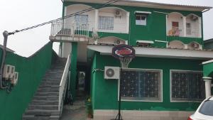 a green building with a basketball hoop in front of it at Aimé Anaïs in Abaga