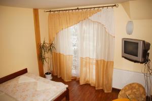una camera con TV e finestra con tende di Pensjonat u Marysi a Pisz