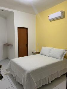 a bedroom with a white bed and a heater at Pousada Villa Galinhos in Galinhos