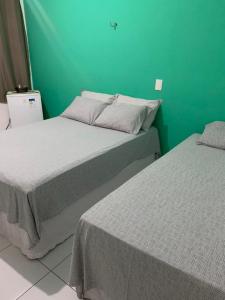 2 camas en una habitación con una pared verde en Pousada Villa Galinhos, en Galinhos