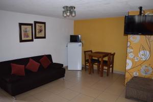 ein Wohnzimmer mit einem Sofa, einem Tisch und einem Kühlschrank in der Unterkunft Hotel Santa Lucia del Bosque in San Luis Potosí
