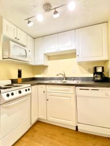 a white kitchen with white cabinets and a sink at Siesta Beach Cottage, Sleeps 6, Walk to Beach, Stores, & Restaurants in Siesta Key