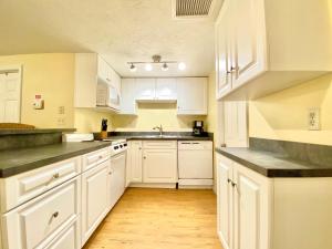 a white kitchen with white cabinets and a wooden floor at Siesta Beach Cottage, Sleeps 6, Walk to Beach, Stores, & Restaurants in Siesta Key