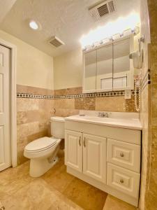 a bathroom with a toilet and a sink and a mirror at Siesta Beach Cottage, Sleeps 6, Walk to Beach, Stores, & Restaurants in Siesta Key