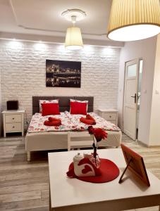 a bedroom with two beds with red pillows and a table at Best Studio in Wrocław